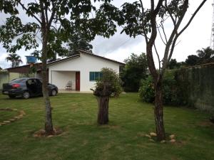 a house with a car parked in a yard with two trees at Singela Casa em Chapada dos Guimarães in Chapada dos Guimarães