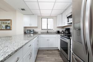 cocina con armarios blancos y encimeras de granito en Gulfside 503 by Brooks and Shorey Resorts condo, en Fort Walton Beach