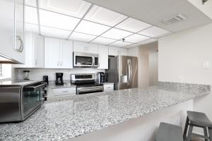 cocina con armarios blancos y encimera de granito en Gulfside 503 by Brooks and Shorey Resorts condo, en Fort Walton Beach