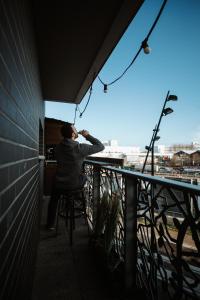 un homme assis dans une chaise sur un balcon et parlant sur un téléphone portable dans l'établissement L'Échappée Parisienne - Canal St-Denis, à Aubervilliers