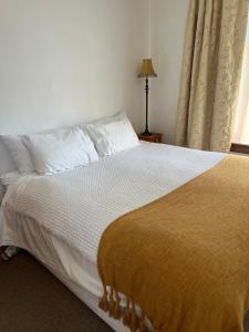 a bedroom with a bed with white sheets and a window at The Old Vicarage in Reefton