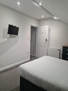a white bedroom with a bed and a flat screen tv at APARTMENT in BARNSLEY CENTRAL in Barnsley