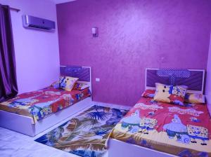 two beds in a room with purple walls at شاليه بالريف الاوربي للاجازات in Giza