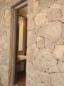 pared de piedra en el baño con lavabo en Casa Atamisque en San Rafael
