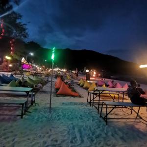 una playa por la noche con gente sentada en sillas de playa en Haadrin Village near the pier, en Haad Rin