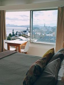 a bedroom with a bed and a large window with a table at Nothofagus Apartments in San Carlos de Bariloche