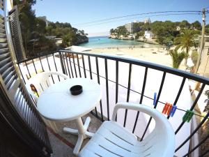 a balcony with a table and two chairs and a beach at Hostal Playa in Cala Santanyi