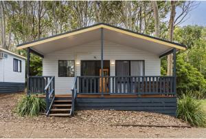 ein kleines weißes Cottage mit einer großen Veranda in der Unterkunft Discovery Parks - Narooma Beach in Narooma