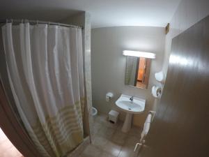 y baño con cortina de ducha y lavamanos. en Hostal Playa en Cala Santanyi