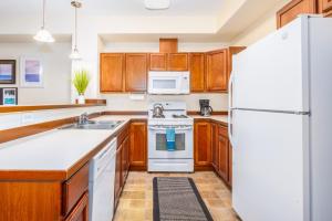 a kitchen with wooden cabinets and a white refrigerator at Harmony Hills #229 in Anchorage