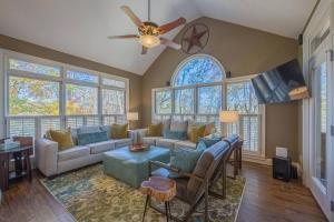un soggiorno con divano e ventilatore a soffitto di Large Luxury House, 4 King Beds & 21 Total, Hot Tub, Theater, Fireplace, Game Room, Ping-pong, Pool Table, Air Hockey, Arcade, River, Big Kitchen, Nice Porch, Quiet, Good for Families and Large Groups, Near UGA Golf Course, Close to UGA & Stanford Stadium ad Athens
