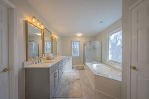Baño blanco con 2 lavabos, bañera y tubermott en Large Luxury House, 4 King Beds & 21 Total, Hot Tub, Theater, Fireplace, Game Room, Ping-pong, Pool Table, Air Hockey, Arcade, River, Big Kitchen, Nice Porch, Quiet, Good for Families and Large Groups, Near UGA Golf Course, Close to UGA & Stanford Stadium en Athens