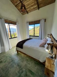 um quarto com uma cama grande e 2 janelas em La Casita de Charo 2 em Constanza