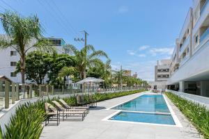 una piscina con tumbonas junto a un edificio en Cannes Club Residence a 200m da praia, recém inaugurado, en Florianópolis