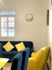 uma sala de estar com um sofá azul e cadeiras amarelas em Centrico Apartamento Barrio de La Exposición na Cidade do Panamá