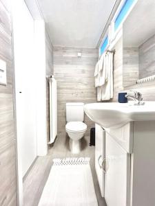 a white bathroom with a toilet and a sink at Bright Tiny Studio - Shared Pool & Sauna - Free Parking - Air condition in Muralto