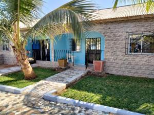 Lamin的住宿－Faith and Grace Guest House，前面有棕榈树的蓝色房子