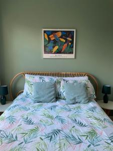 a bed with two pillows and a picture on the wall at By the Pagoda- cozy garden flat by Richmond & Kew Gardens in Kew Gardens