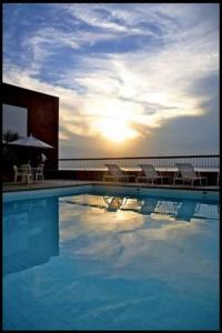 uma piscina com cadeiras, uma mesa e um guarda-sol em Victória Marina Flat - 1202 em Salvador