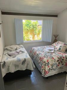 una camera da letto con due letti e una finestra di Casa Vila Tortuga a Arraial d'Ajuda