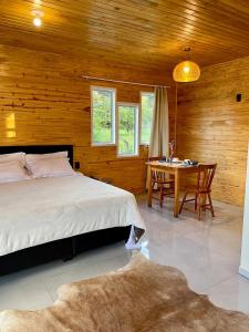 a bedroom with a bed and a table in it at Cabanas Kuntze in Urubici