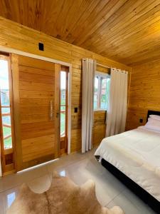 a bedroom with a bed and wooden walls and windows at Cabanas Kuntze in Urubici
