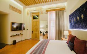 a bedroom with a bed and a television in a room at Casa Azulai Puebla Hotel Boutique in Puebla