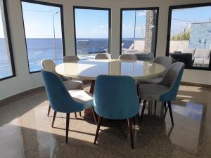 a dining room with a table and blue chairs at Villa Sunset Avenue in Paul do Mar