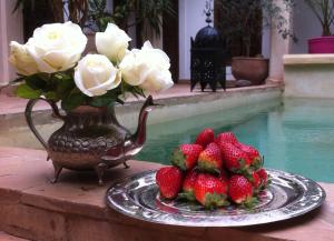 um prato de morangos e um vaso de rosas brancas em Riad Mandalay em Marrakech