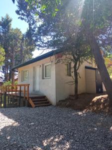 una pequeña casa con un árbol delante en La Casita de las Vertientes en San Carlos de Bariloche