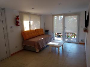 1 dormitorio con cama, banco y ventanas en La Casita de las Vertientes en San Carlos de Bariloche