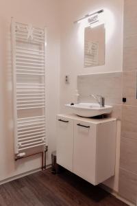 a white bathroom with a sink and a mirror at Apartmány Centrum in Nový Bor