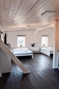 two beds in a large room with a wooden ceiling at Apartmány Centrum in Nový Bor