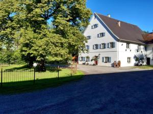 een groot wit huis met een hek ervoor bij Rösslerhof Ferienwohnung Stiller Bach 