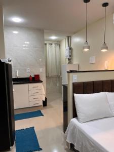 1 Schlafzimmer mit einem weißen Bett und einer Küche in der Unterkunft Loft 215 da Lapa, Rio de Janeiro in Rio de Janeiro