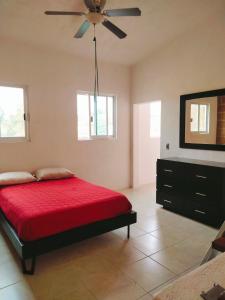 - une chambre avec un lit rouge et un ventilateur de plafond dans l'établissement Casa de Scarlett, à Cocoyoc