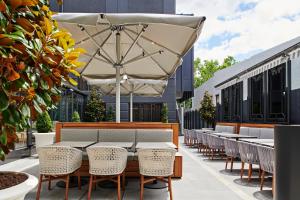 un patio al aire libre con mesas, sillas y una sombrilla en The Royce en Melbourne