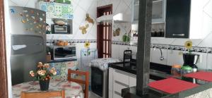 una cocina con nevera y una mesa con flores en Casa da Lena, en Arraial do Cabo