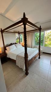 Casa Zazen Praia dos Carneiros - Club Meridional في بريا دوس كارنيروس: غرفة نوم مع سرير مظلة في غرفة مع نوافذ