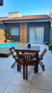 una mesa de madera y 2 sillas en el patio en Casa com piscina em Guaratuba PR en Guaratuba