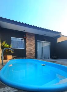 uma grande piscina azul em frente a uma casa em Casa com piscina em Guaratuba PR em Guaratuba