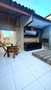 un patio con una mesa de madera y un banco en Casa com piscina em Guaratuba PR en Guaratuba
