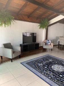 sala de estar con TV, sofá y alfombra en Cobertura Dos Amores Na melhor localização da Praia Brava- Balneário Camboriú, en Balneário Camboriú