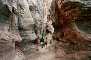 2 personnes marchant à travers un canyon de fentes dans l'établissement AutoCamp Zion, à Virgin
