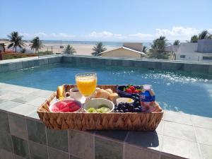 a tray of food and a glass of juice next to a pool at CASA Rio Mar Paripueira in Paripueira