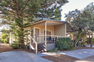 ein kleines gelbes Haus mit einer Veranda und einer Treppe dahin in der Unterkunft NRMA Sydney Lakeside Holiday Park in Narrabeen