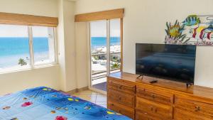 een slaapkamer met een flatscreen-tv en een bed bij Spectacular 2 Bedroom Condo on Sandy Beach at Las Palmas Resort B-504 condo in Puerto Peñasco