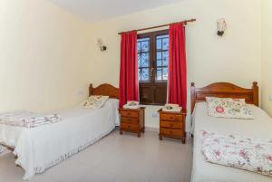 コスタ・テギセにあるPatricioのベッドルーム1室(ベッド2台付)、赤いカーテン付きの窓が備わります。