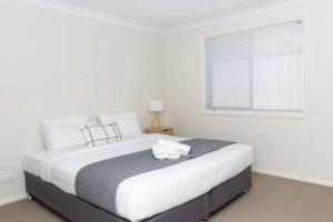 - une chambre blanche avec un grand lit et une fenêtre dans l'établissement Lovely 3 Bed, 2 Bath in the City Centre!, à Wagga Wagga