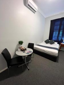 a room with a bed and a table and a chair at Adelaide Pulteney Motel in Adelaide